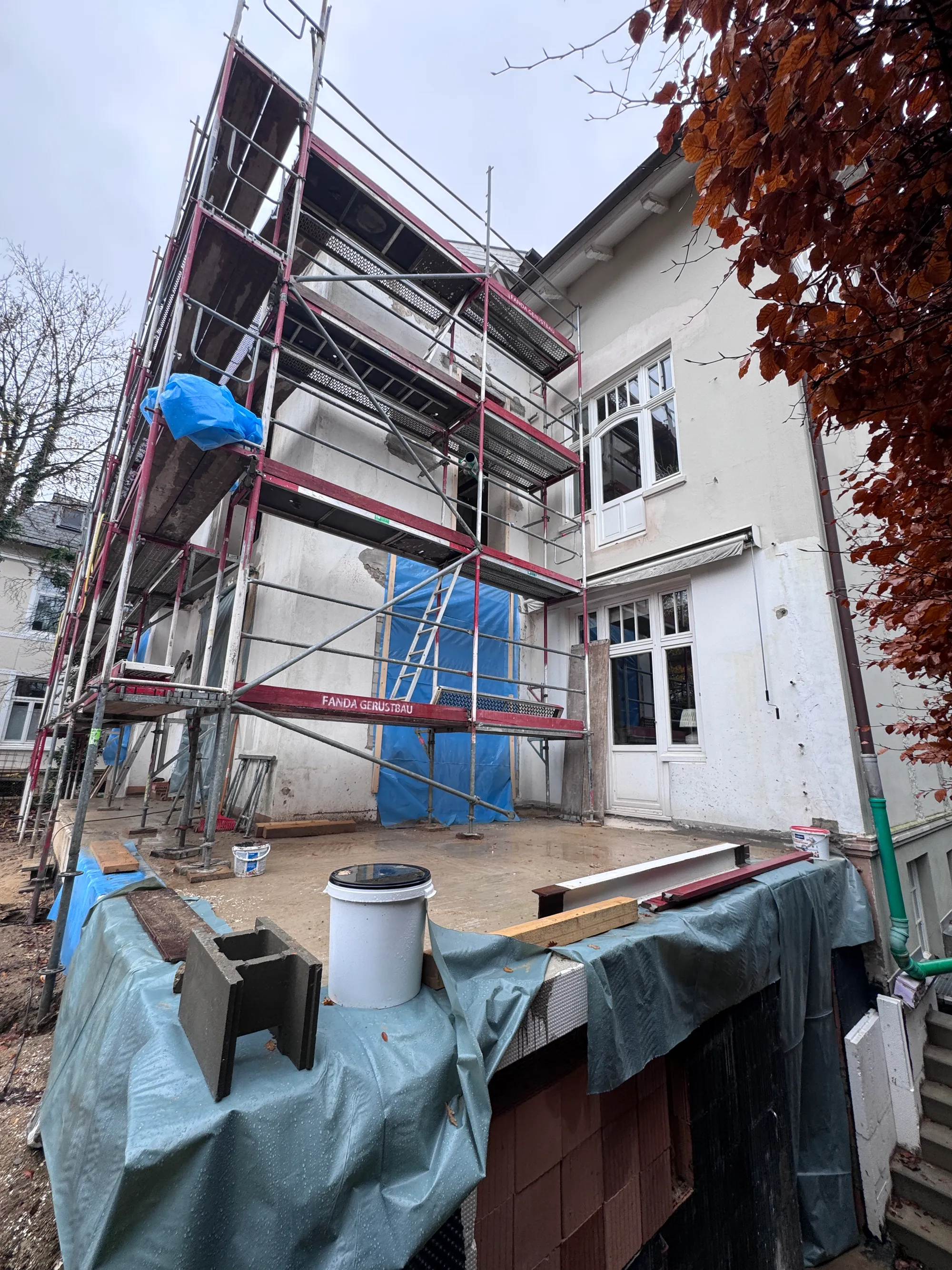 Rückseite der Villa in Blankenese während der Fassadendämmung, eingerüstet, mit abgeschlagenem Putz und Schutzfolie