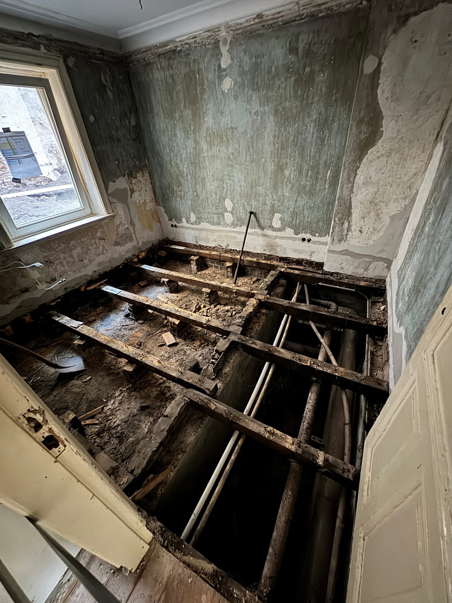 Entkernter Innenraum im Denkmal-MFH mit freigelegtem Dielenboden und historischer Stuckdecke